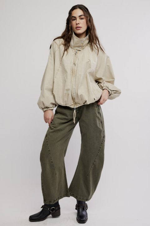Woman wearing beige jacket and green pants on white background