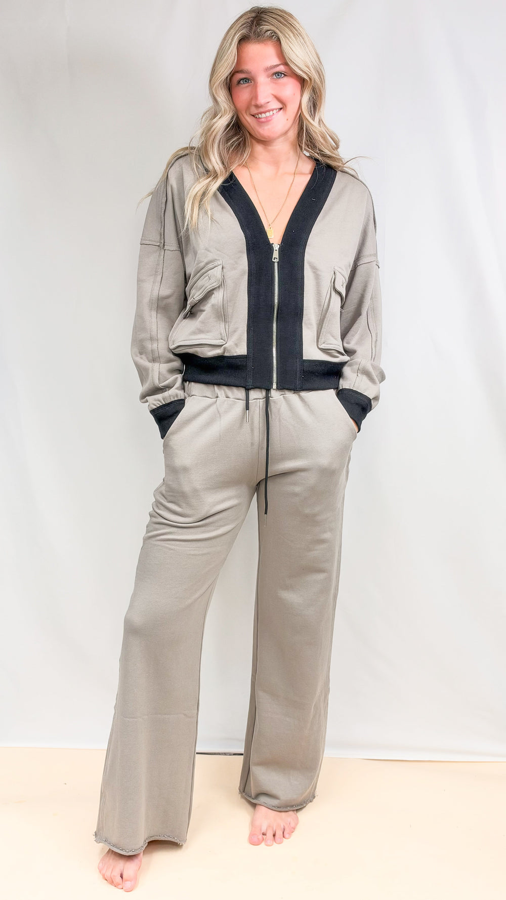 Woman wearing matching beige set with black details on plain background