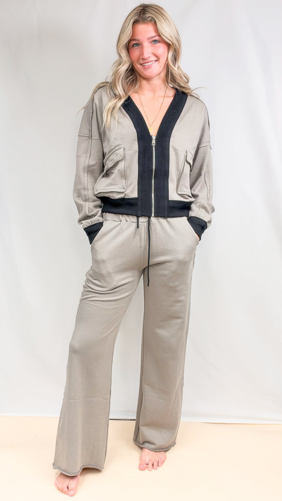 Woman wearing matching beige set with black details on plain background