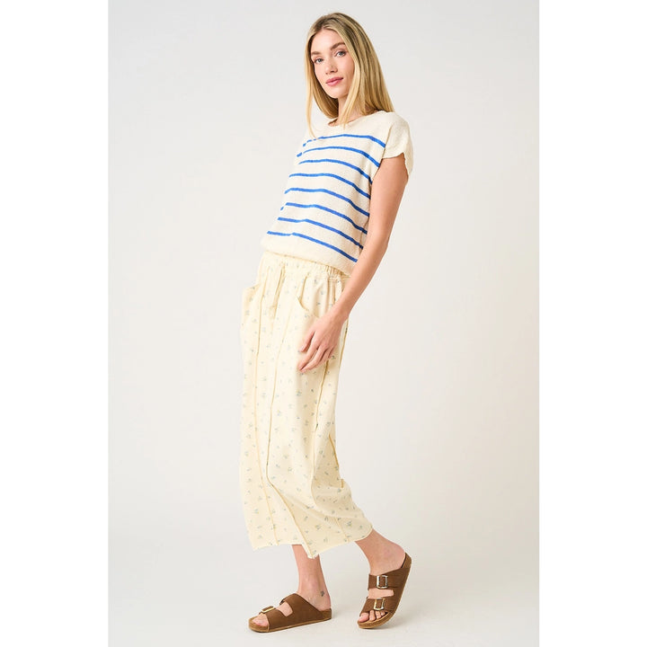 Woman wearing a striped shirt and light-colored pants on a white background