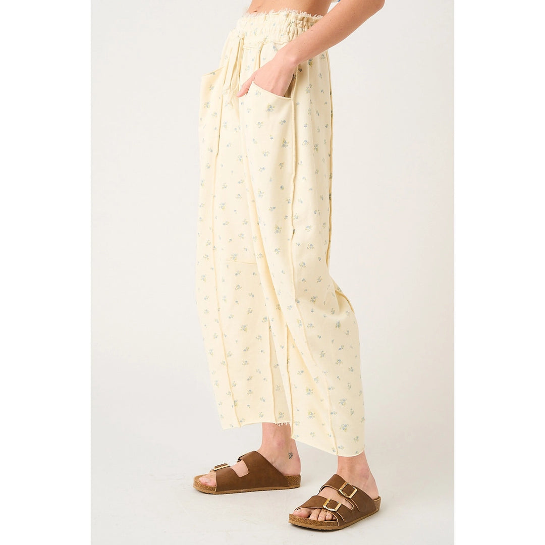 Person wearing cream-colored pants with a subtle pattern, paired with brown sandals on a white background.