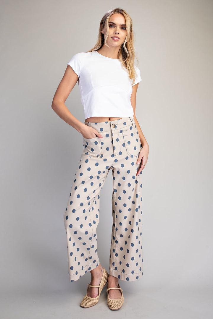 Woman wearing a white crop top and patterned pants on a gray background