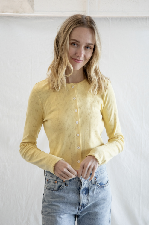Woman wearing yellow cardigan and jeans on plain background