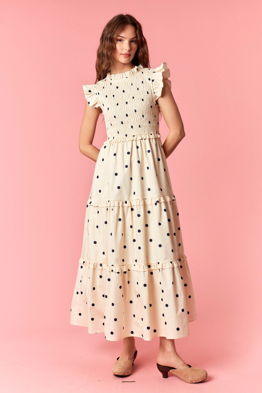 Woman wearing a polka dot dress on a pink background