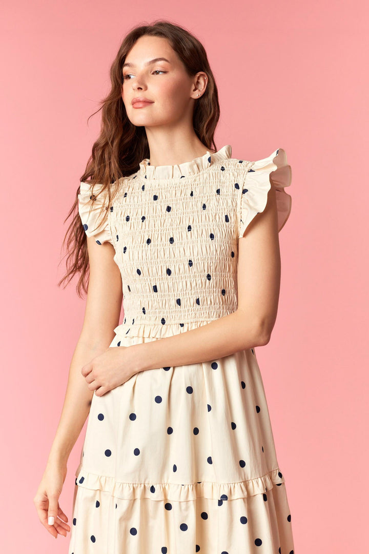 Woman wearing a polka dot dress against a pink background