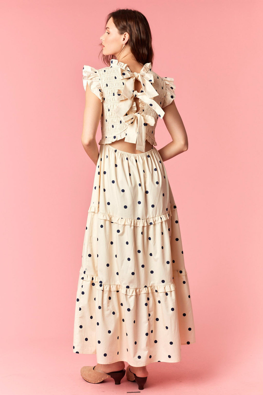 Woman wearing a polka dot outfit with a top and skirt on a pink background