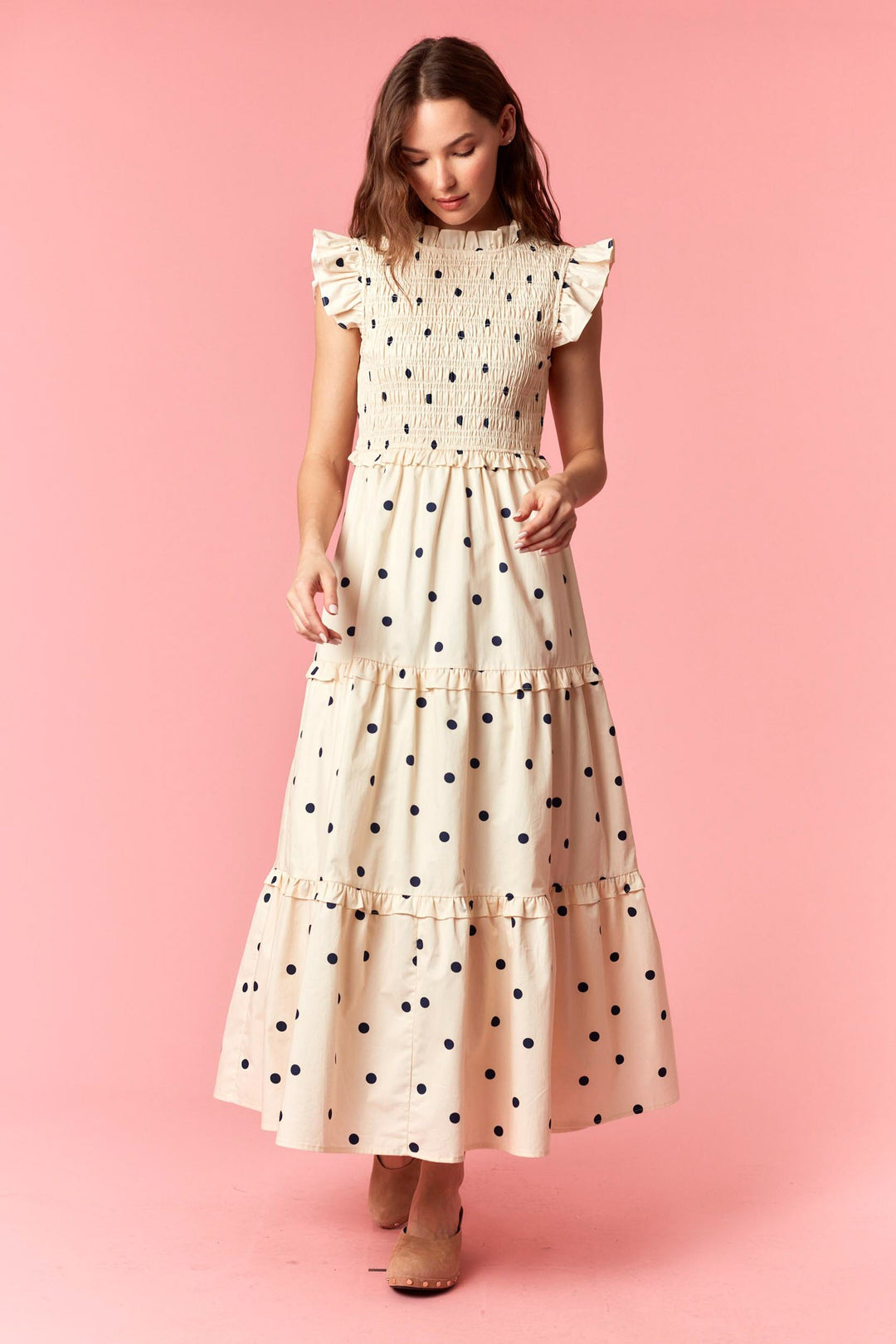Woman wearing a polka dot dress against a pink background