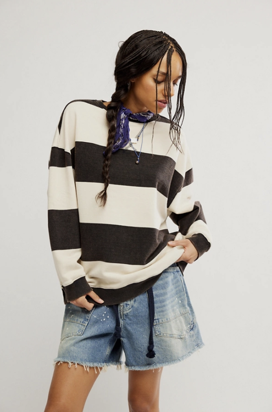 Woman wearing a black and white striped sweater with denim shorts on a plain background