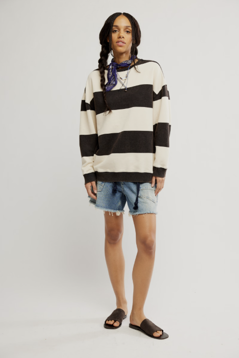Woman wearing black and white stripe crewneck with denim shorts on white background