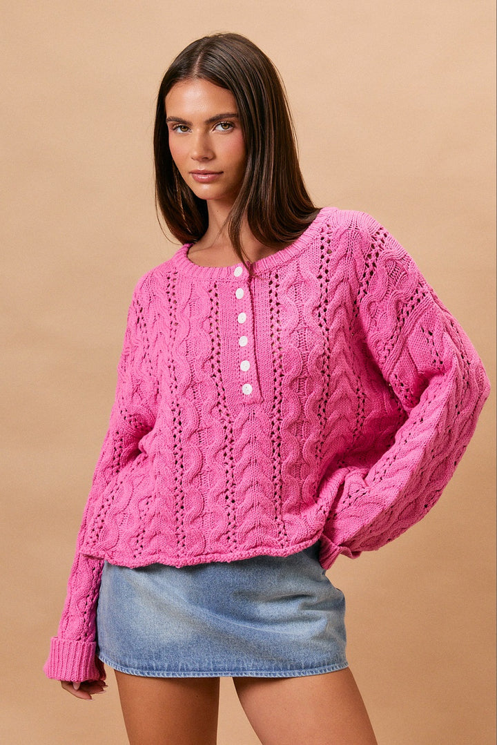 Woman wearing pink cable knit sweater and denim skirt on plain background