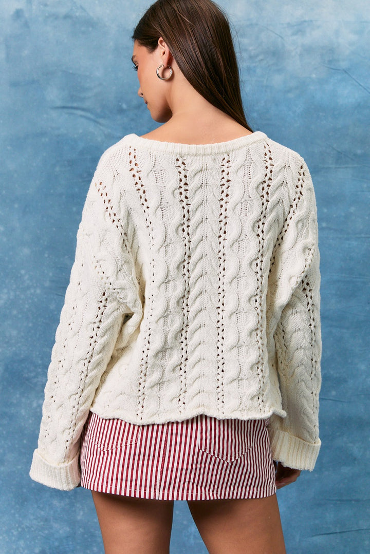 Woman wearing white cable knit sweater and skirt on blue background