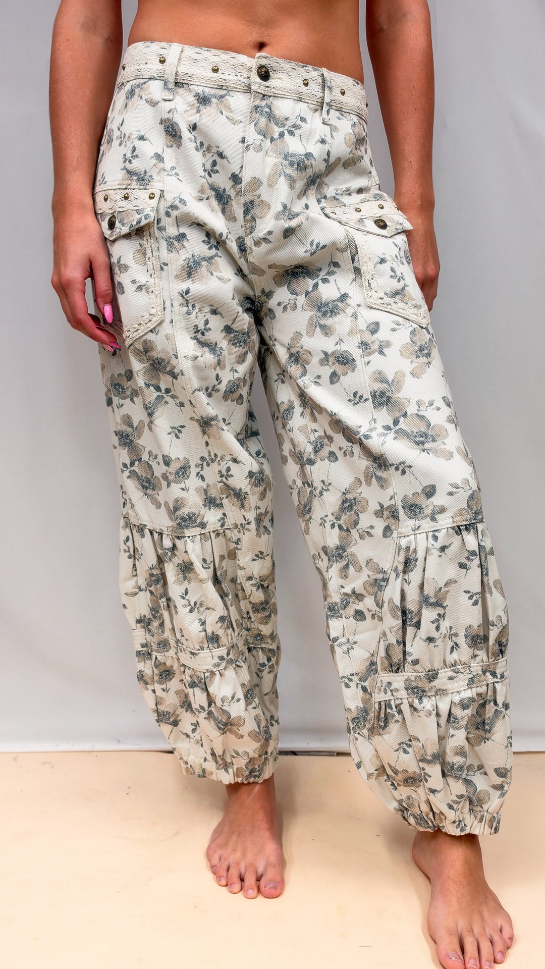 Woman wearing beige floral balloon pants on plain background
