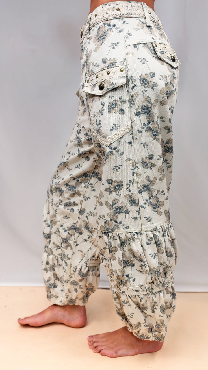 Woman wearing beige floral balloon pants with cargo pockets on plain background