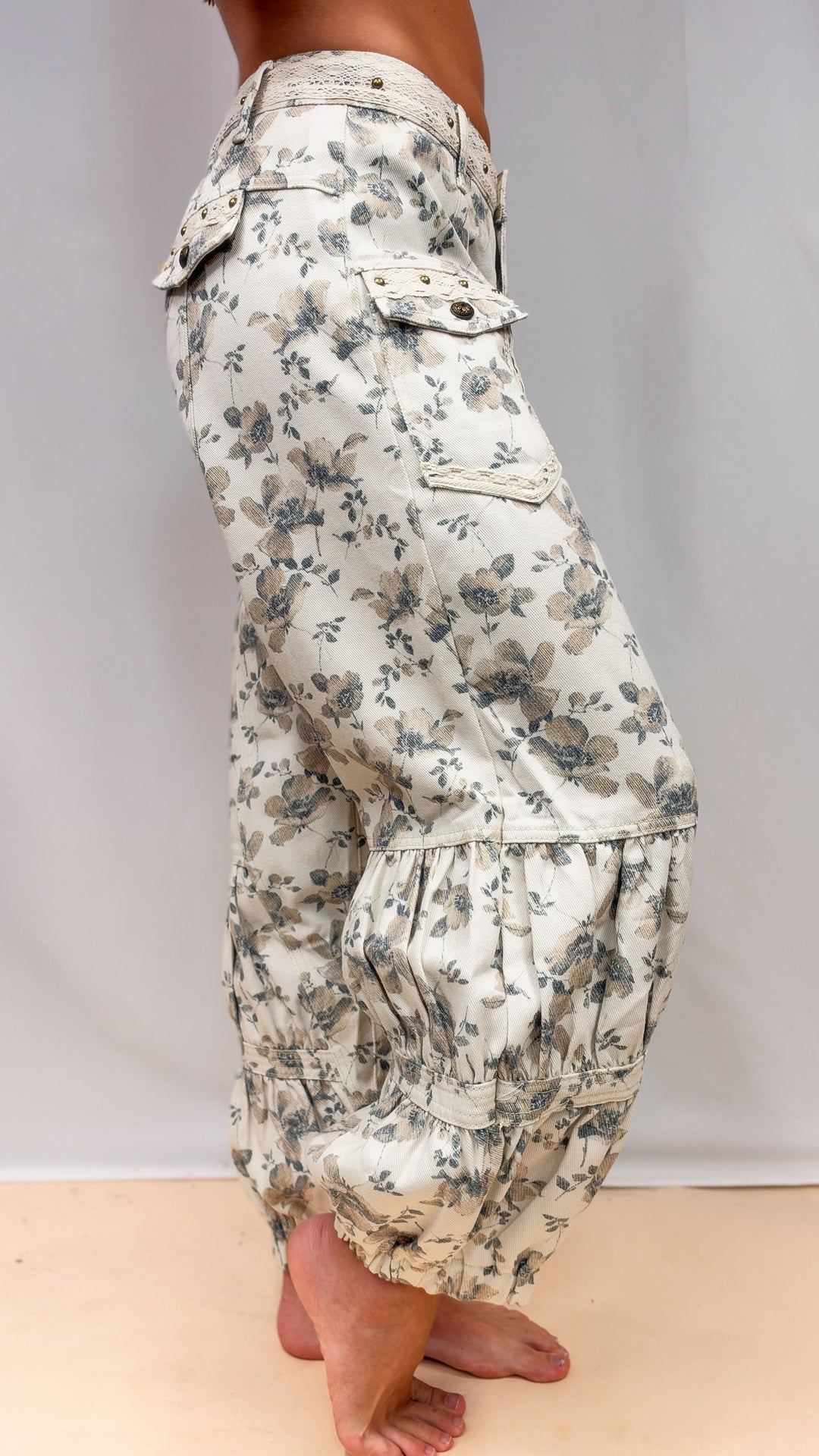 Woman wearing beige floral balloon pants with cargo pockets on plain background