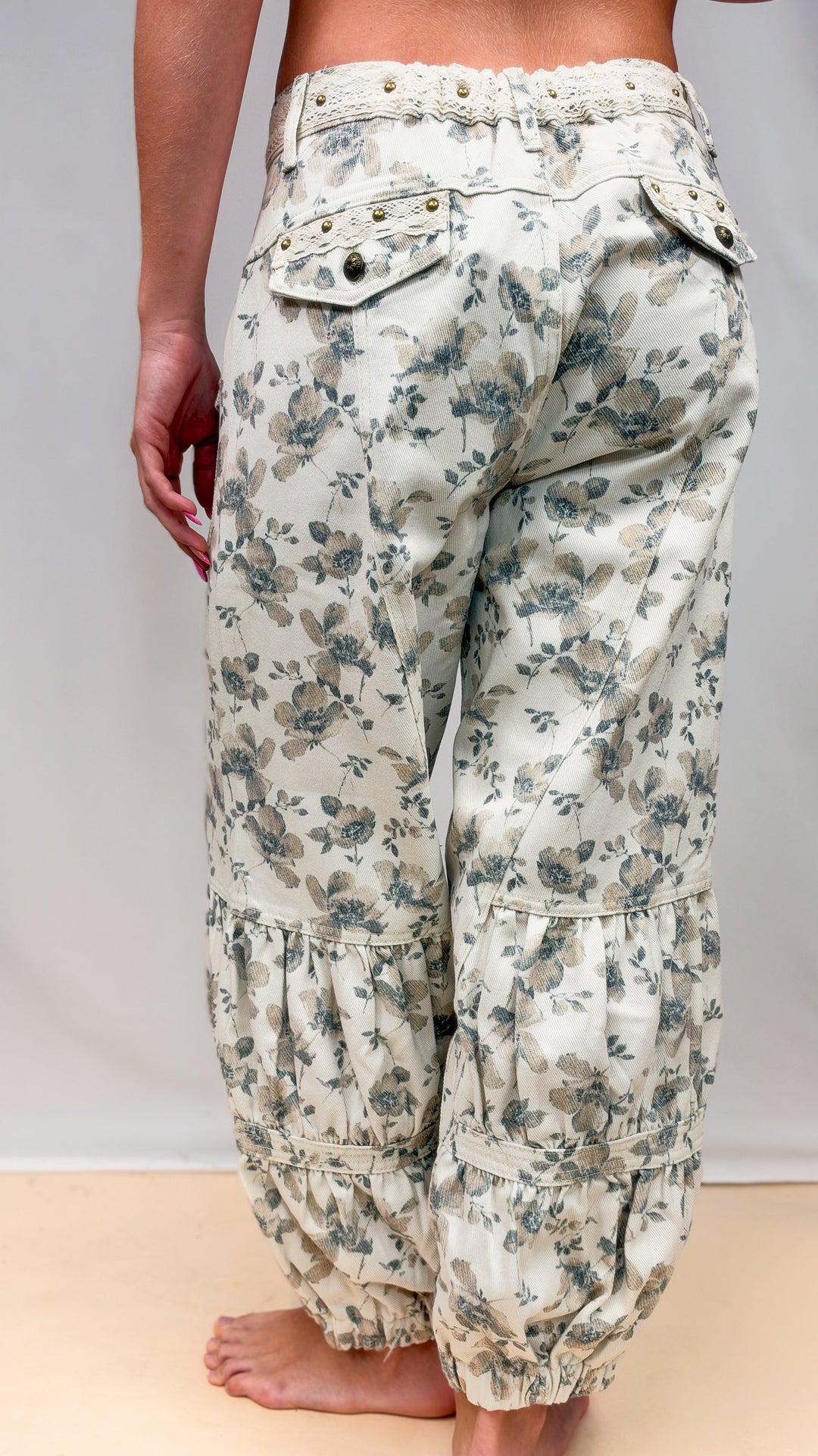 Woman shown from back wearing beige floral balloon pants on plain background