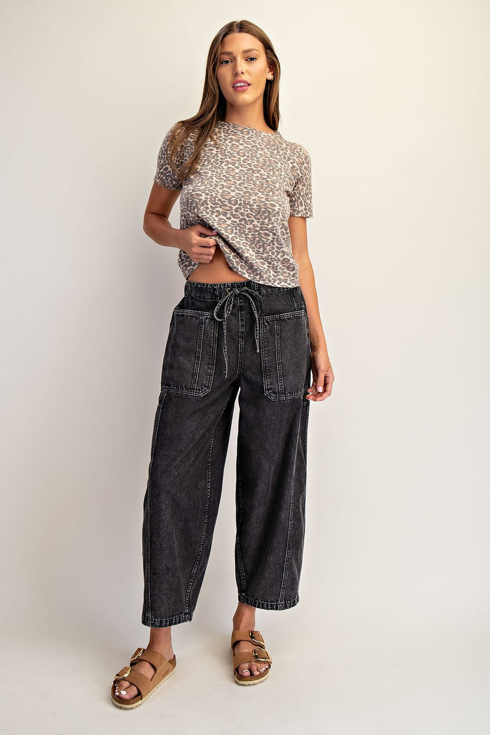 Woman wearing a patterned top and dark jeans on a white background