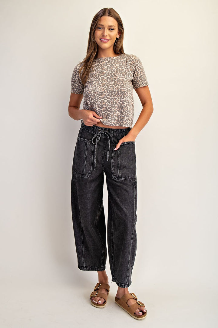 Woman wearing a patterned top and black jeans on a plain background