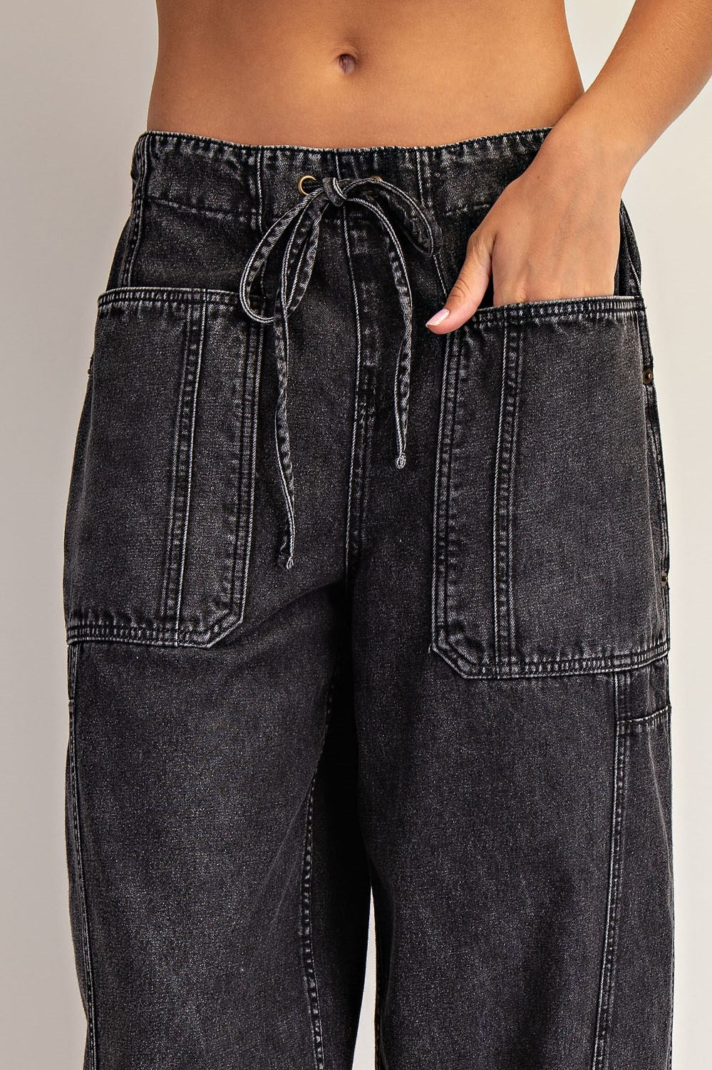 Black denim pants with a drawstring waist on a neutral background