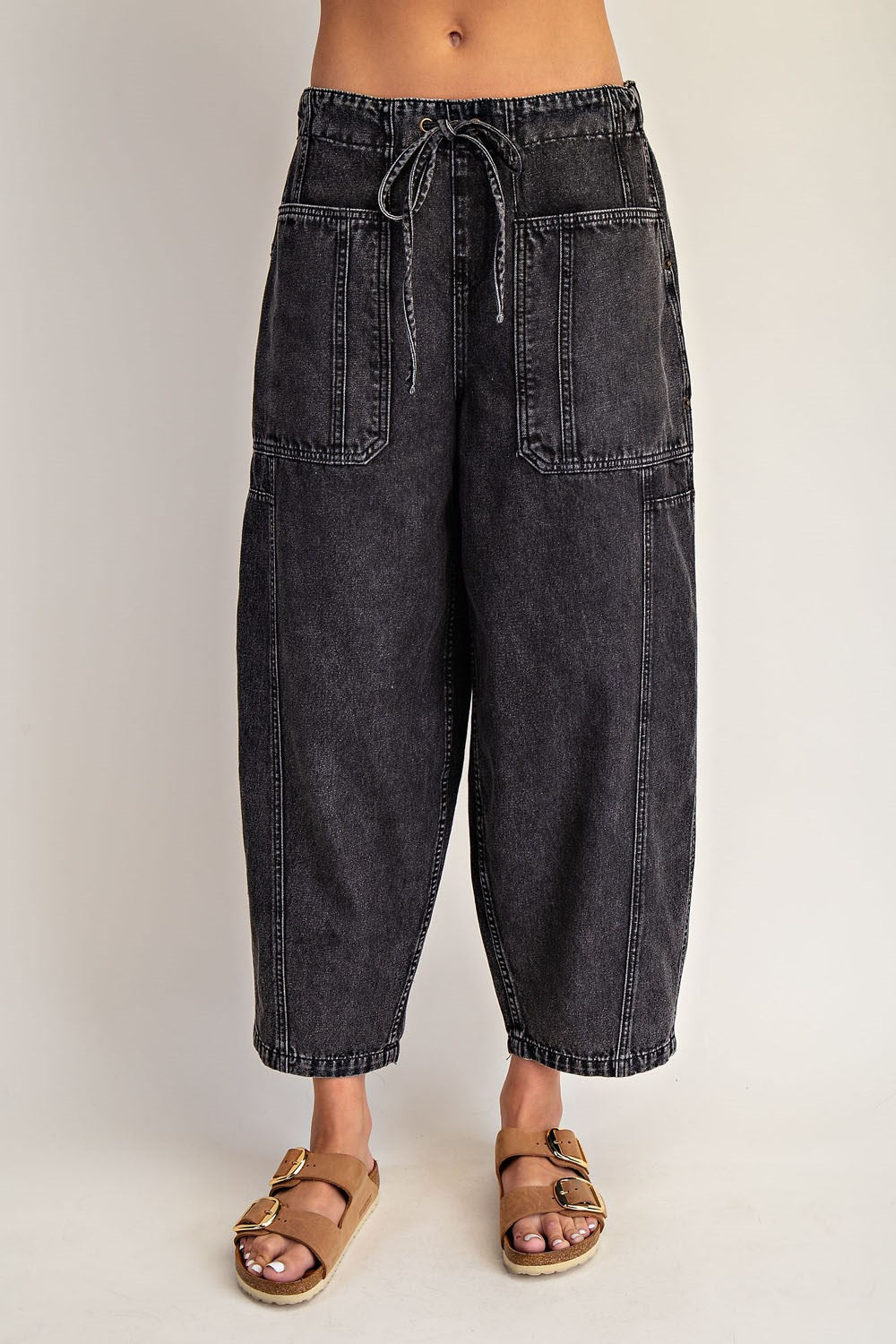 Black denim pants worn by a person on a plain background