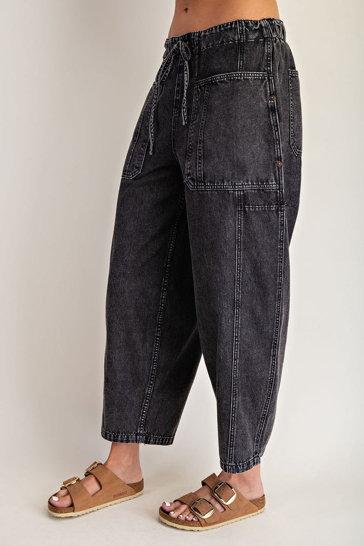 Black denim pants worn by a person on a plain background