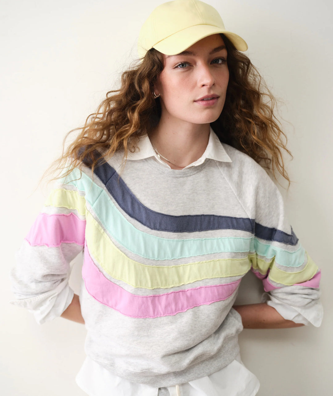 Woman wearing grey sweatshirt with stripes on plain background