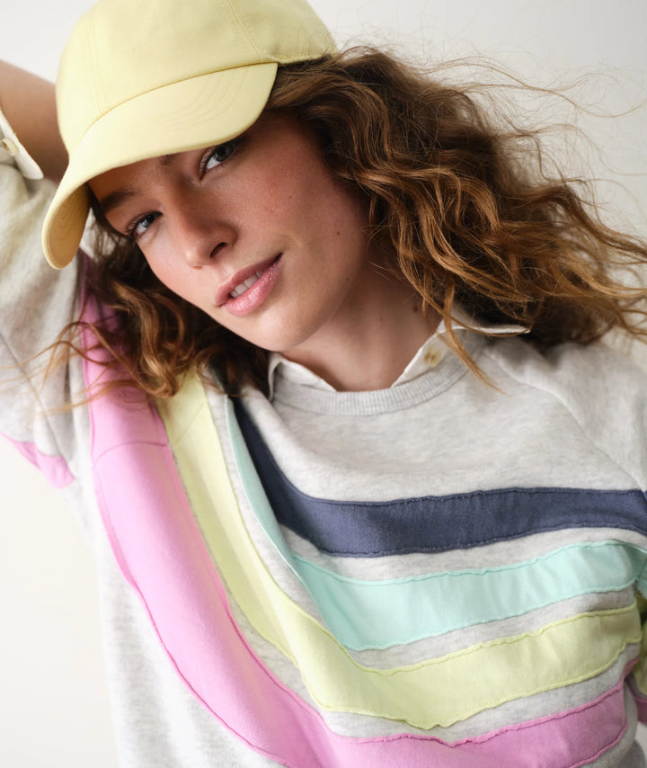 Woman wearing a yellow cap and colorful striped sweater on a white background