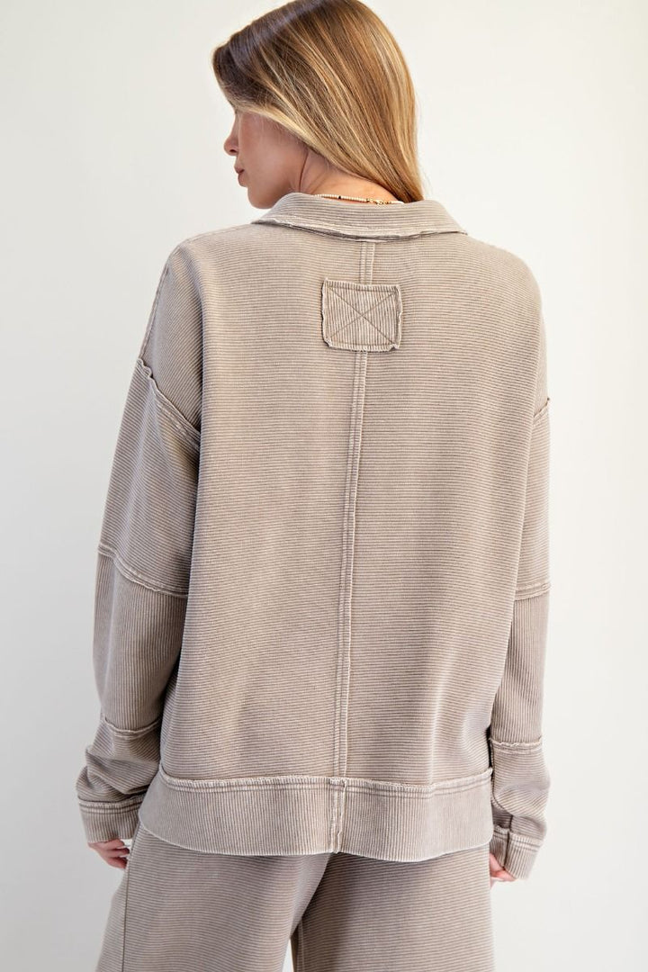Person wearing a beige jacket with a pocket on a white background