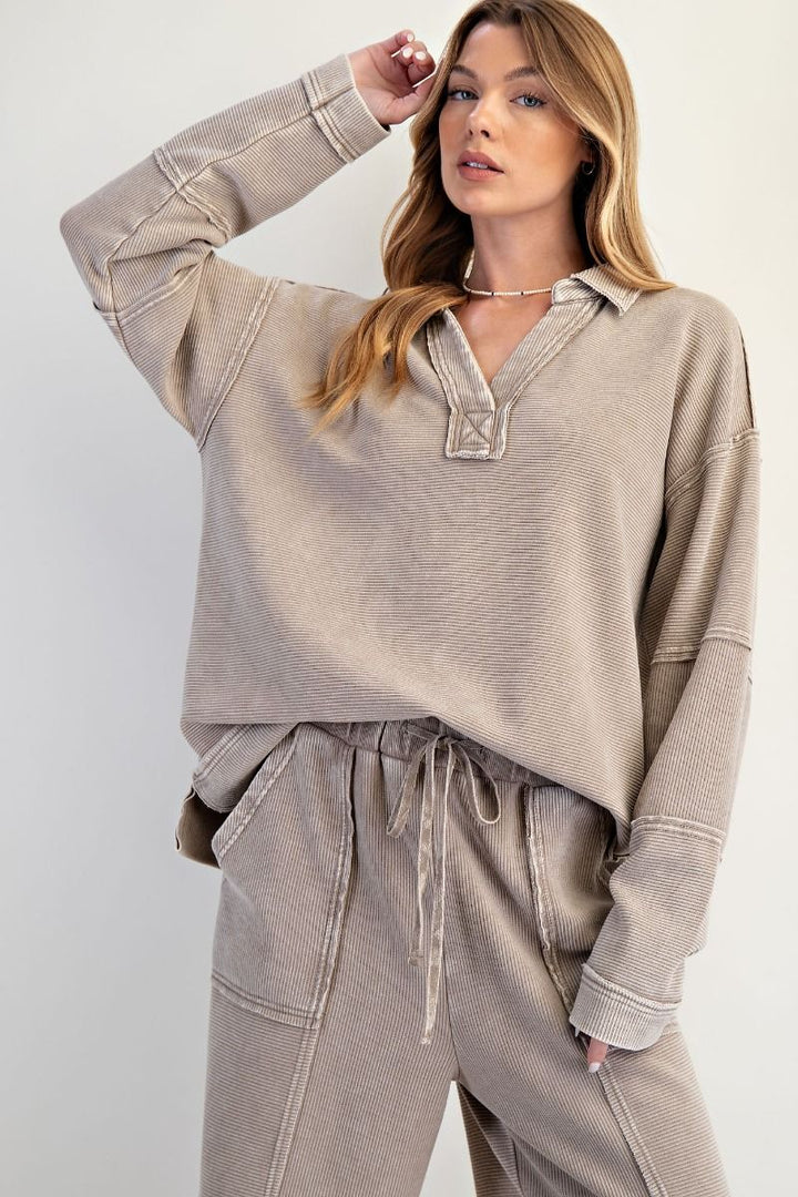 Woman wearing a beige long-sleeve top and pants against a white background