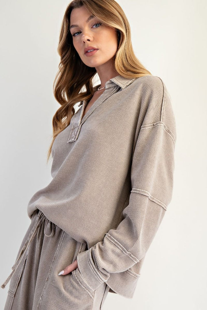Woman wearing a beige ribbed sweater over a shirt with a white background