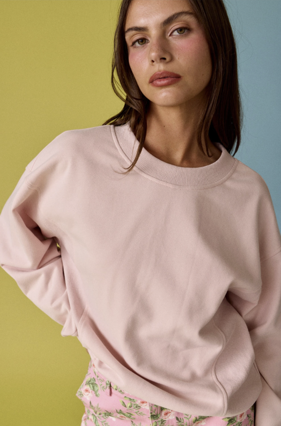 Woman wearing a pink sweatshirt against a gradient background