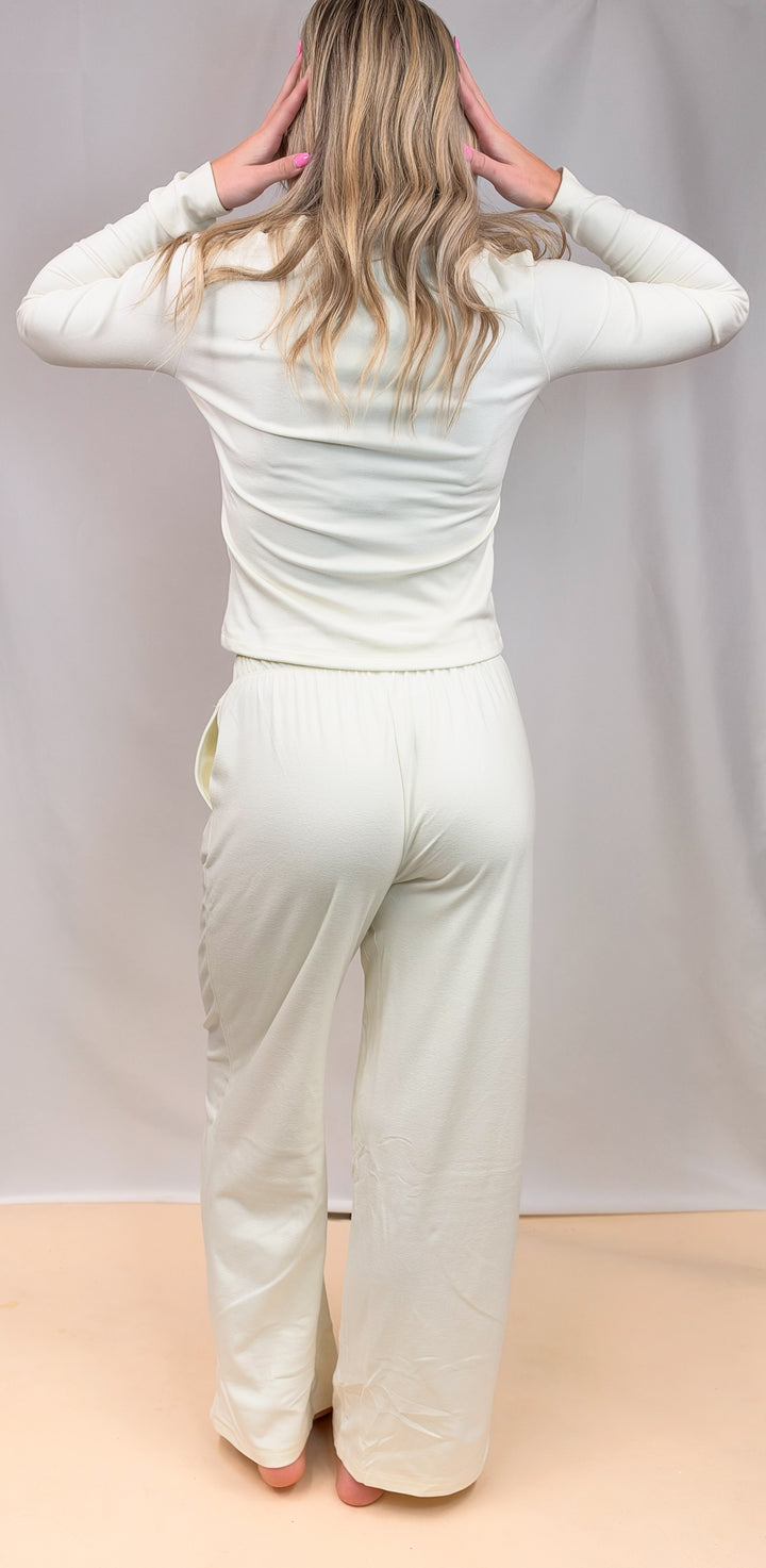 Woman shown from back wearing cream color matching set on plain background