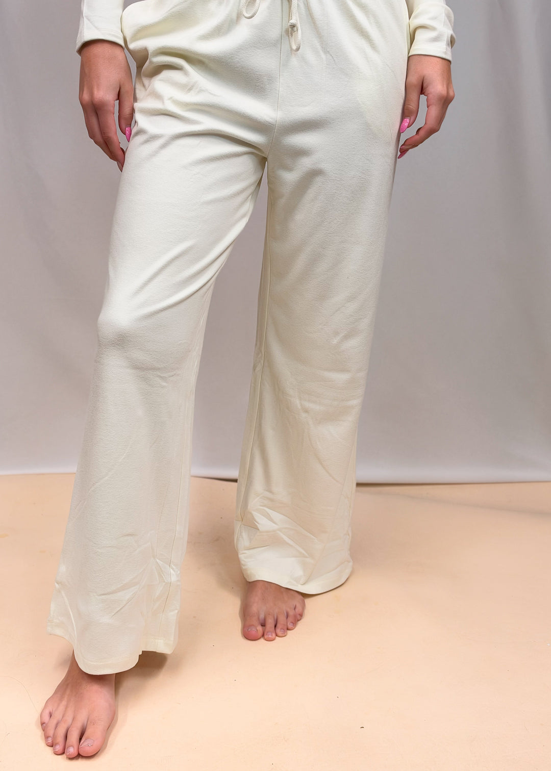 Woman shown from waist down wearing matching cream set on plain background