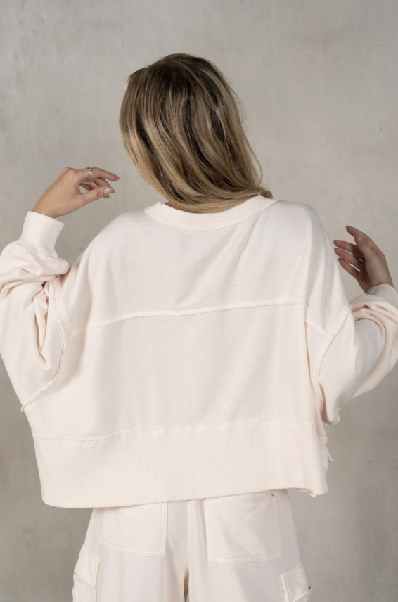 Person wearing a butter oversized sweater against a plain background
