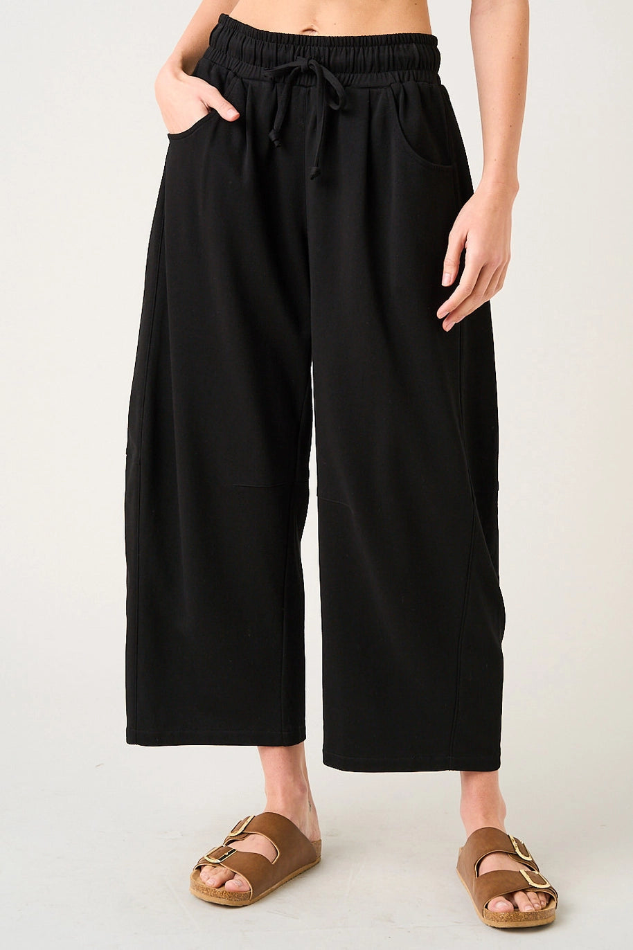 Person wearing black wide-leg pants on a plain background