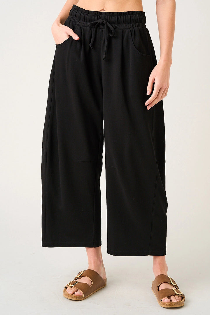 Person wearing black wide-leg pants on a plain background