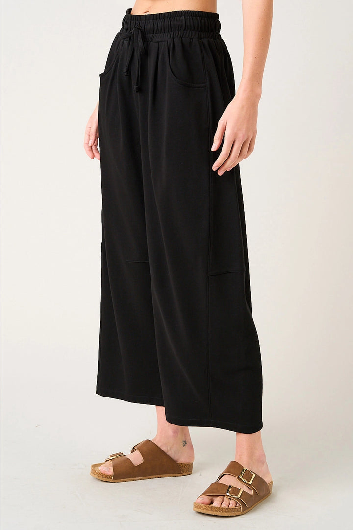 Person wearing black wide-leg pants on a plain background