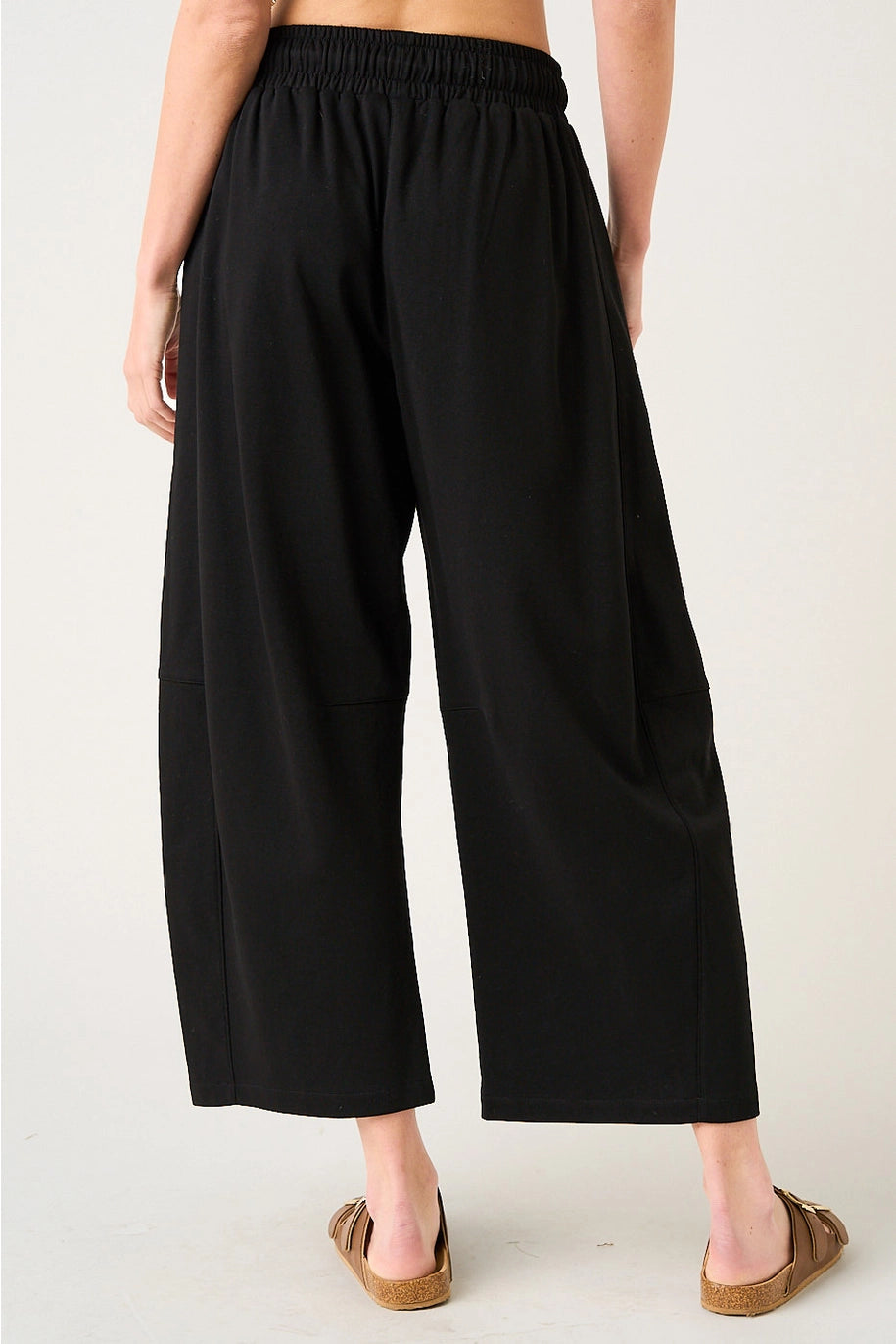 Person wearing black wide-leg pants on a white background