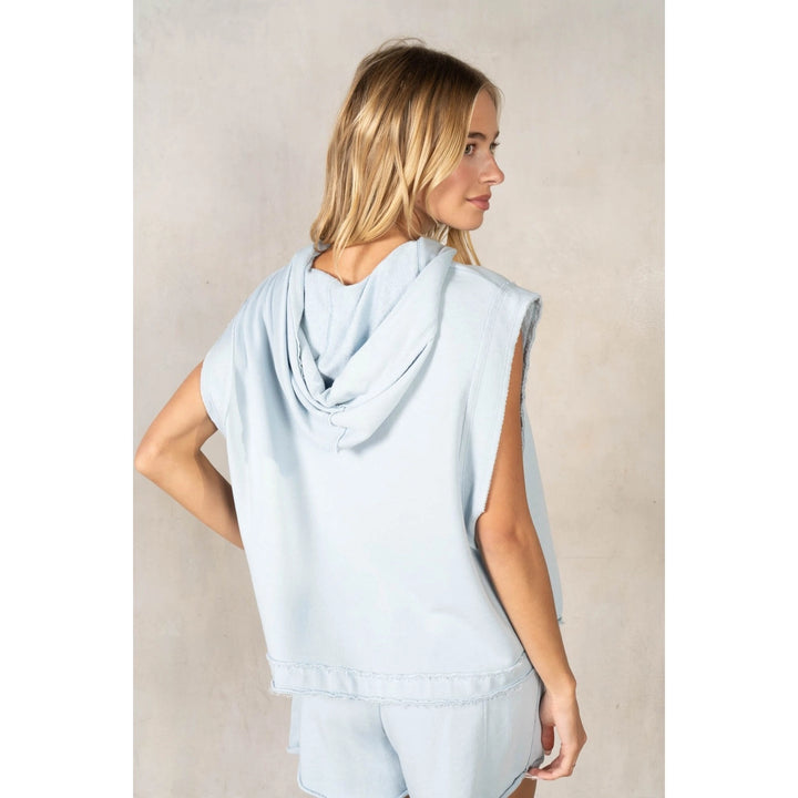Woman wearing a light blue sleeveless top against a neutral background