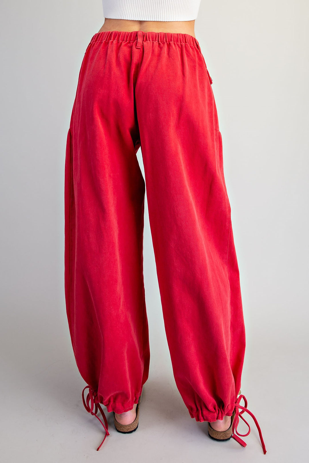 Red wide-leg lounge pants with an elastic waistband and drawstring ankle cuffs, shown on a model from the back against a light gray studio background.