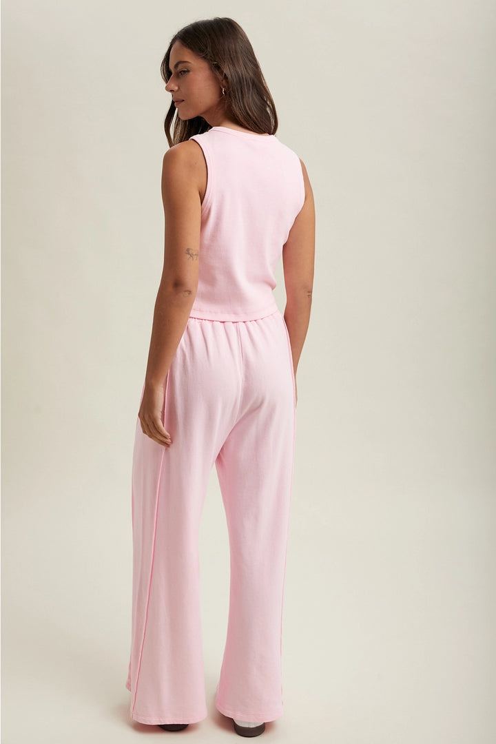 Woman wearing a pink jumpsuit on a plain background