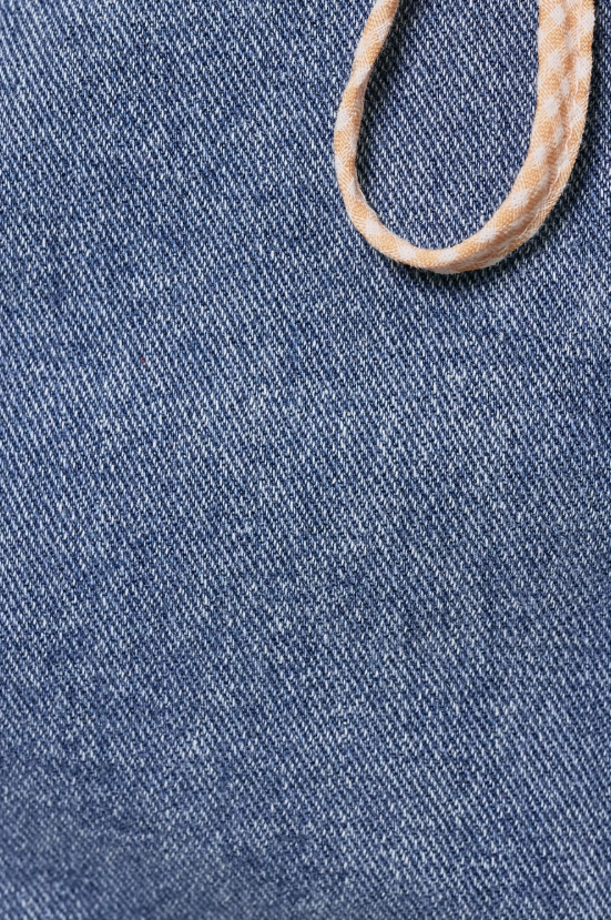 Close-up of blue denim fabric with a beige shoelace.