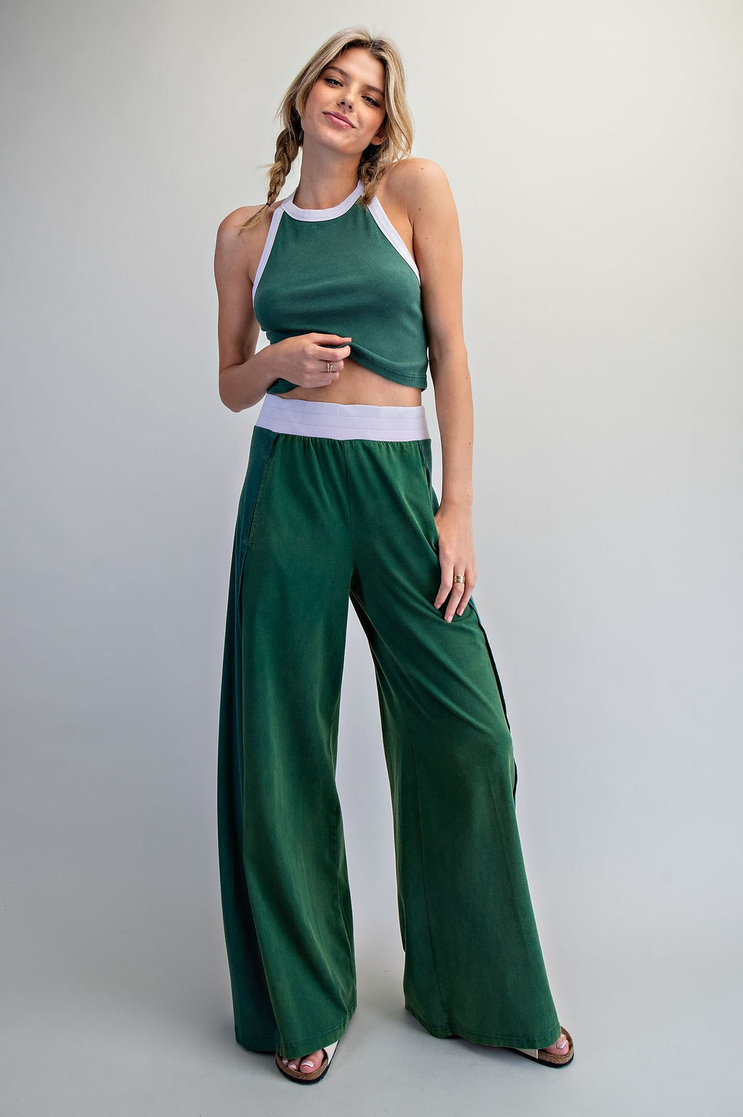 Woman wearing a green outfit with a white waistband on a gray background