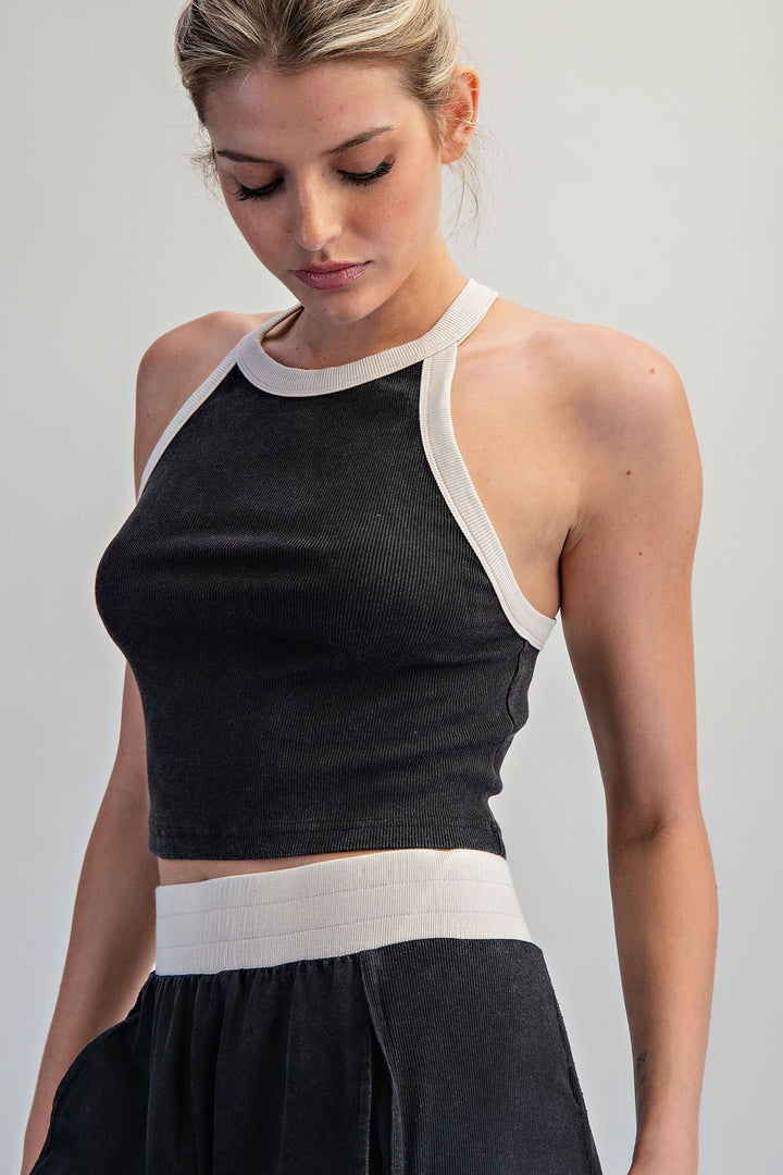 Woman wearing a black and white sleeveless top against a plain background