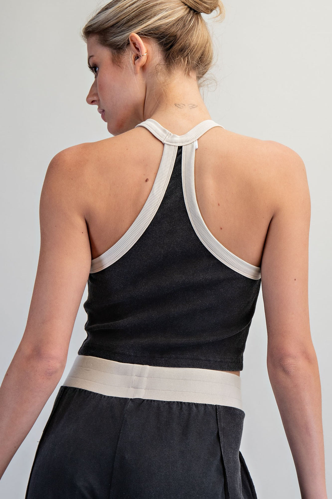Person wearing a black sleeveless top with white trim on a plain background