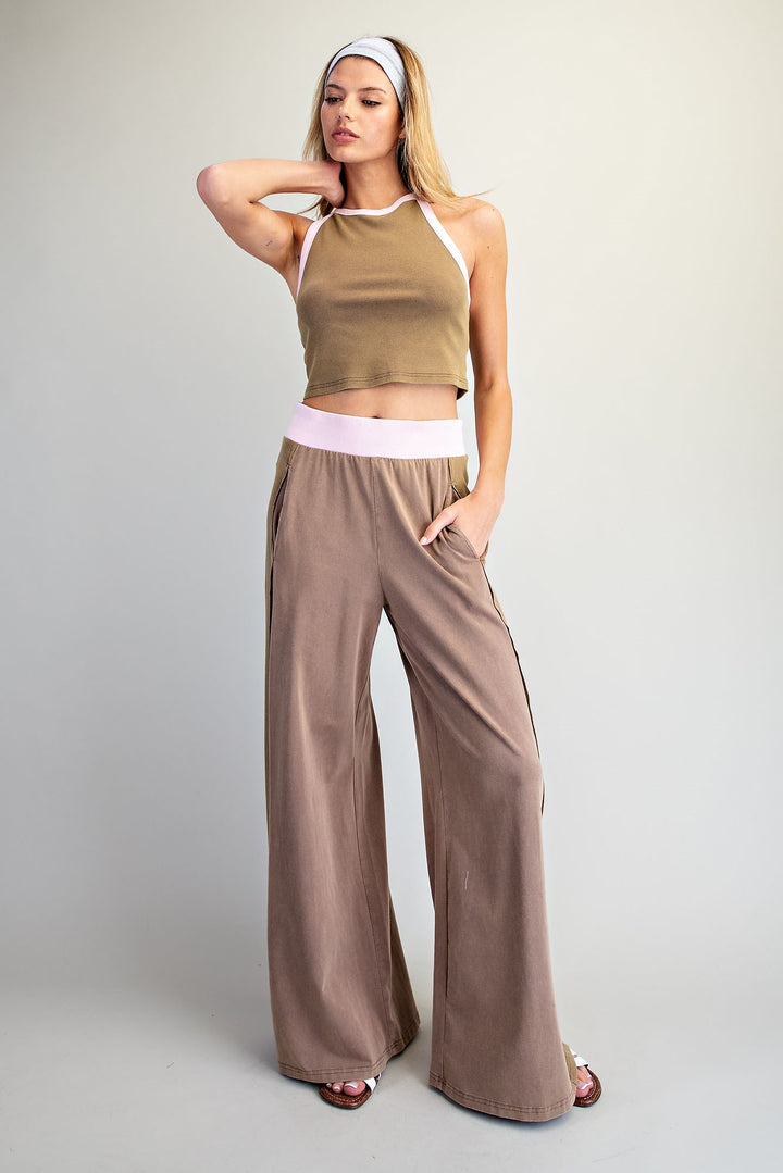Woman wearing a green crop top and brown wide-leg pants on a plain background