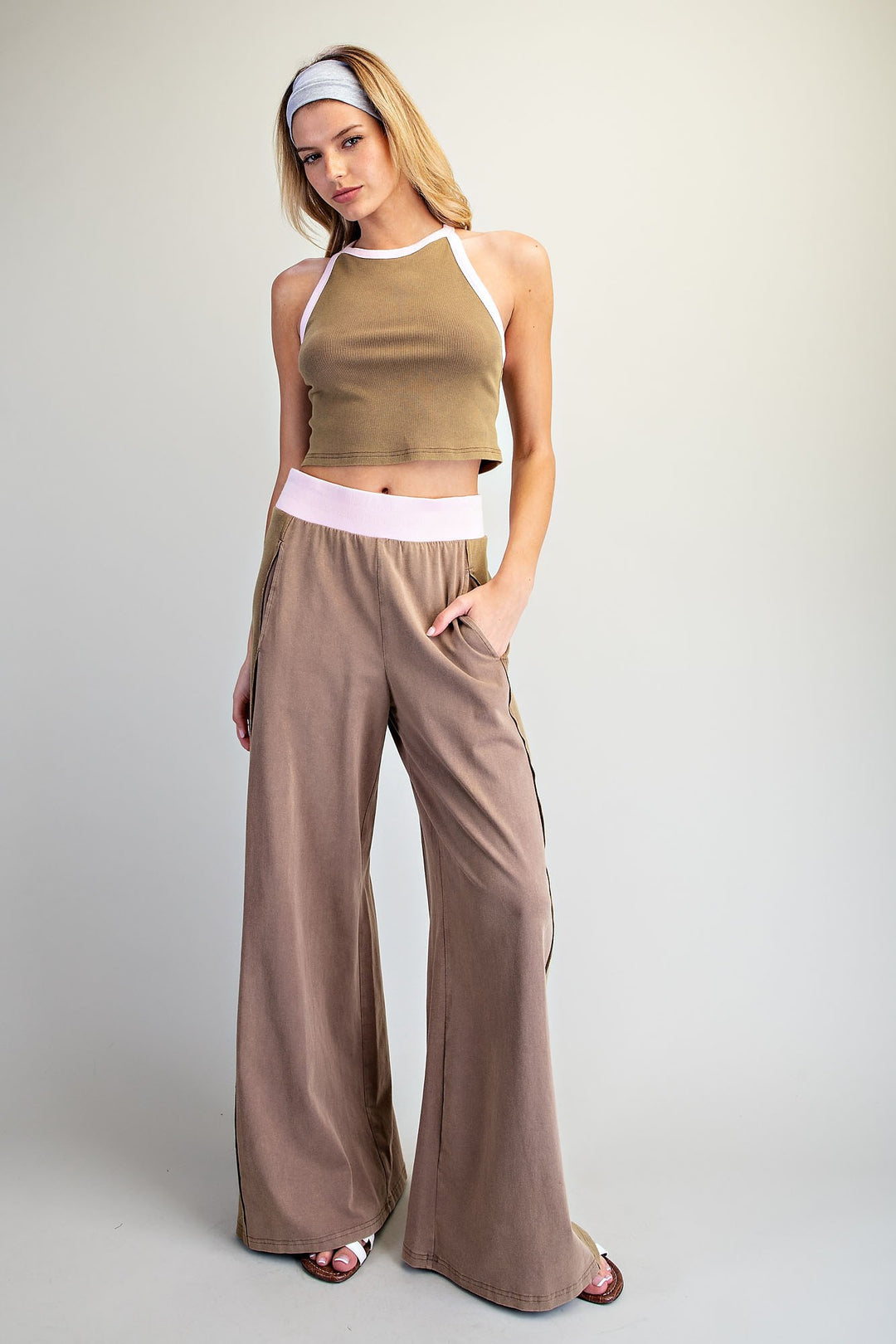 Woman wearing a brown crop top and wide-leg pants on a plain background