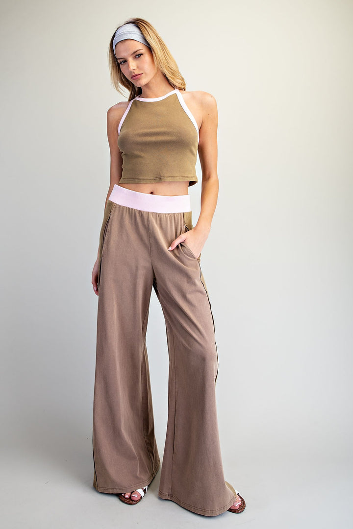 Woman wearing a brown crop top and wide-leg pants on a plain background
