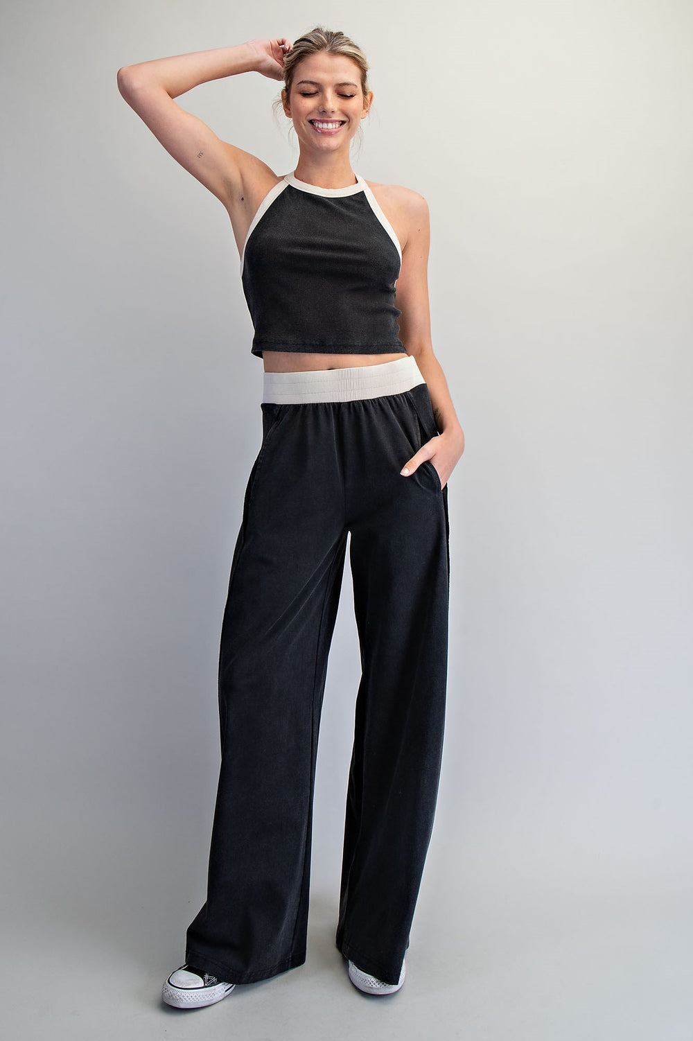 Woman wearing a black and white outfit with wide-leg pants against a plain background
