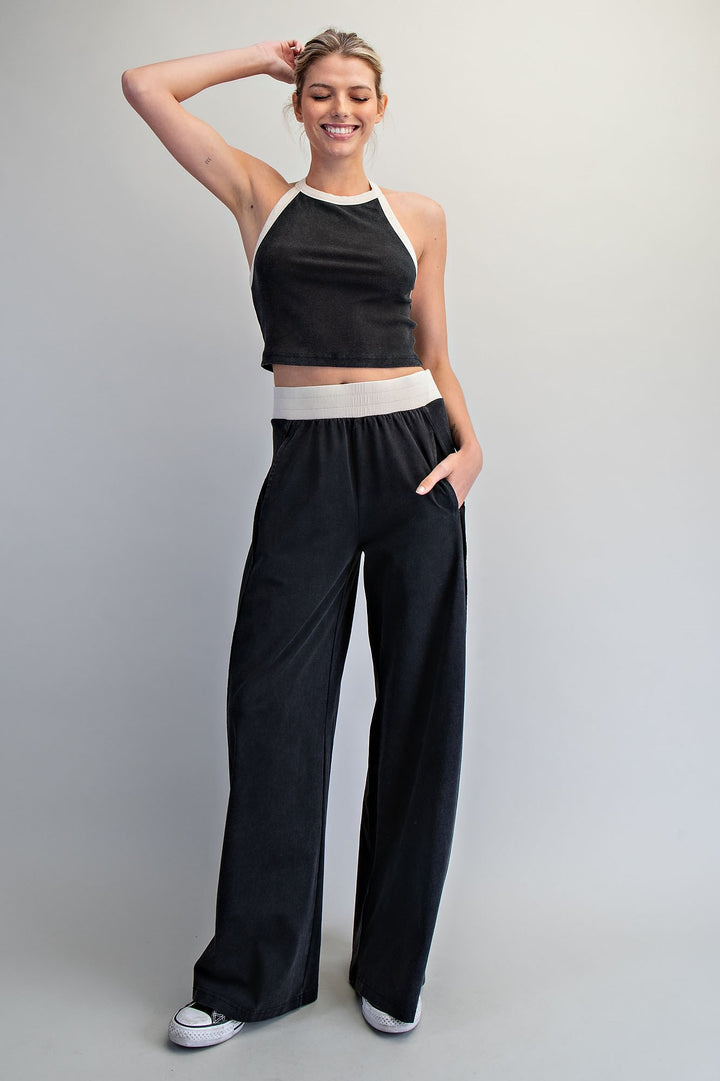 Woman wearing a black and white outfit with wide-leg pants against a plain background