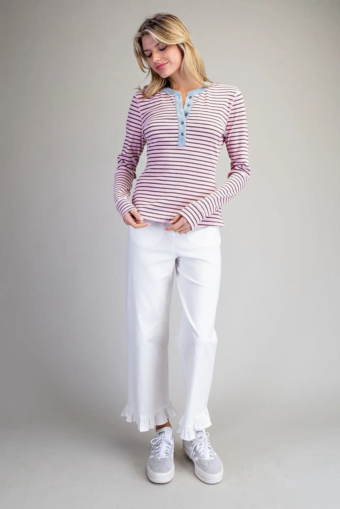Woman wearing a striped shirt and white pants on a plain background